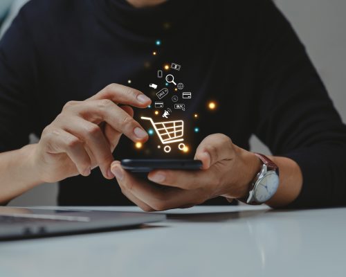 Young man using smartphone with shopping cart icon LR